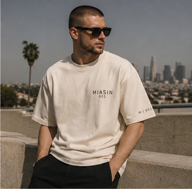 A model wearing the bone MIASIN 001 Box Tee above the Los Angeles skyline
