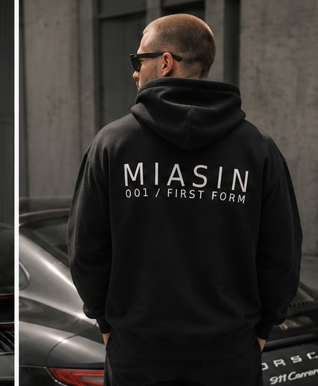 A model photographed from behind wearing the black MIASIN 001 hoodie